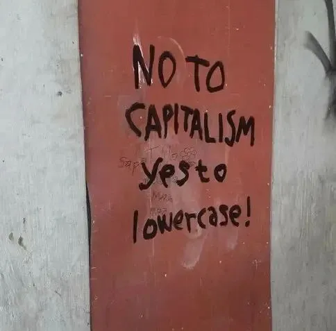 Graffiti on a door spelling "No to capitalism, yes to Lowercase!"