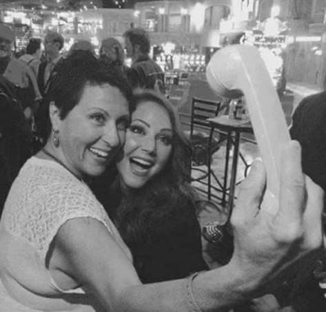 Two girls lookg like they are taking a selfie. They smile to the camera which appears to be an old analogue phone.